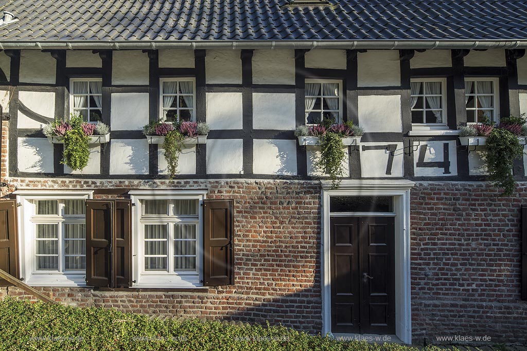 Burscheid-Gruenscheid, Fachwerkfassade mit Haustuere und Fenstern der Gruenscheider Muehle im Abendlicht.