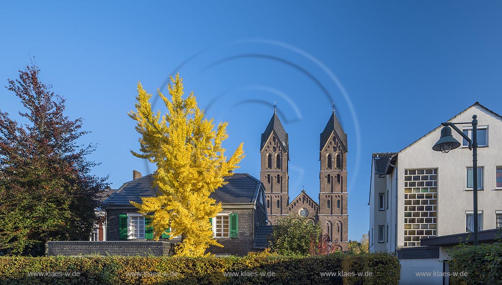 Leverkusen-Schlebusch, Blick auf den Doppelturm der Katholischen St. Andreas Kirche mit herbstlich verfaerbtem Baum.