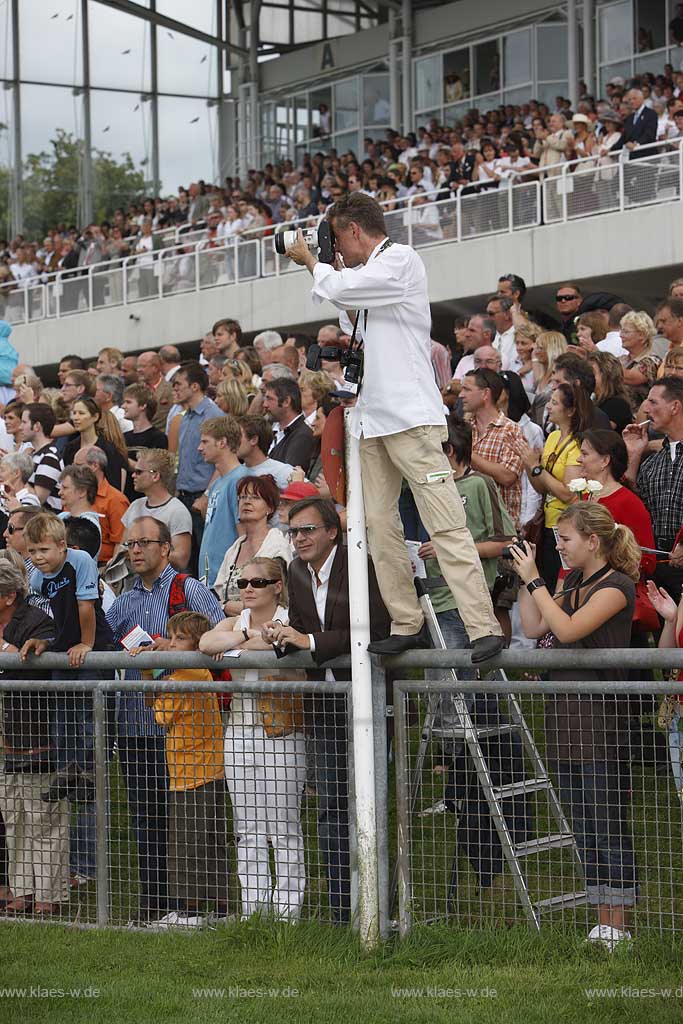 Blick auf das Pferderennen beim 150. Henkel Renntag um den Preis der Diana 2008 in Dsseldorf, Duesseldorf Grafenberg mit Sicht auf Tribuene und Zaungaesten, Fotograf auf einem Zaun beim Fotografieren