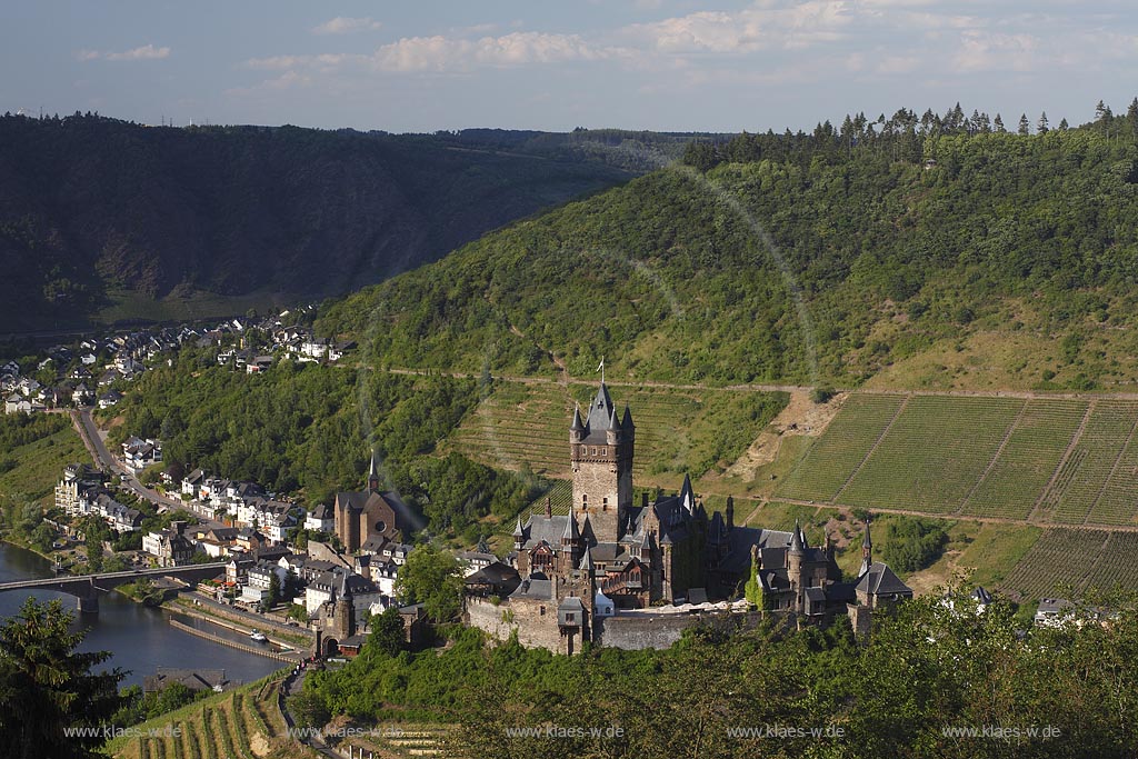 Blick auf Cochem mit Mosel und Reichsburg, die Wahrzeichen von Cochem ist und  auf einem weithin sichtbaren Bergkegel mehr als 100 Meter oberhalb der Stadt steht. Als Gipfelburg gehoert sie zum Typus der Hoehenburgen; view to Cochem with Moselle and Reichsburg.