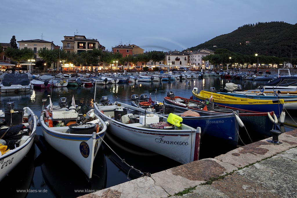 Garda Hafen mit Fischerbooten und dem Piazza Catullo im Hintergrund in Abendstimmung zur blauen Srtunde ; Garda port with fishing boats and piazza Catullo in backgound during blue hour