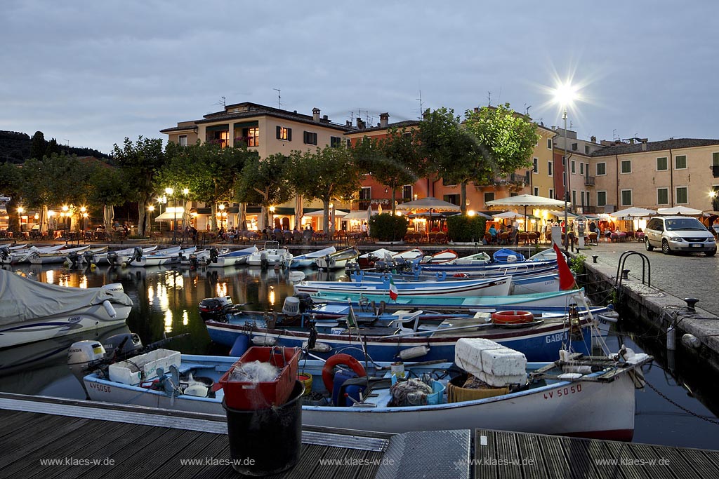 Garda Hafen mit Fischerbooten und dem Piazza Catullo im Hintergrund in Abendstimmung zur blauen Srtunde ; Garda port with fishing boats and piazza Catullo in backgound during blue hour