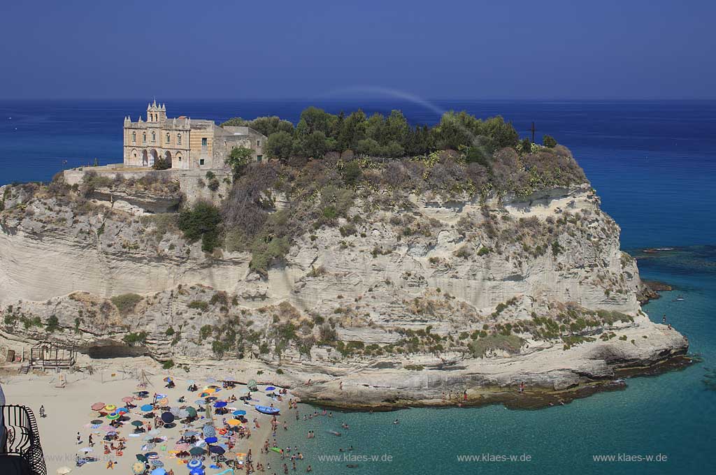 Blick auf die auf einem Felsen gelegene Wallfahrtskirche Chiesa Santa Maria dell'Isola in Tropea, Kalabrien, Italien mit Sicht auf das Meer und Menschen, Touristen am Strand