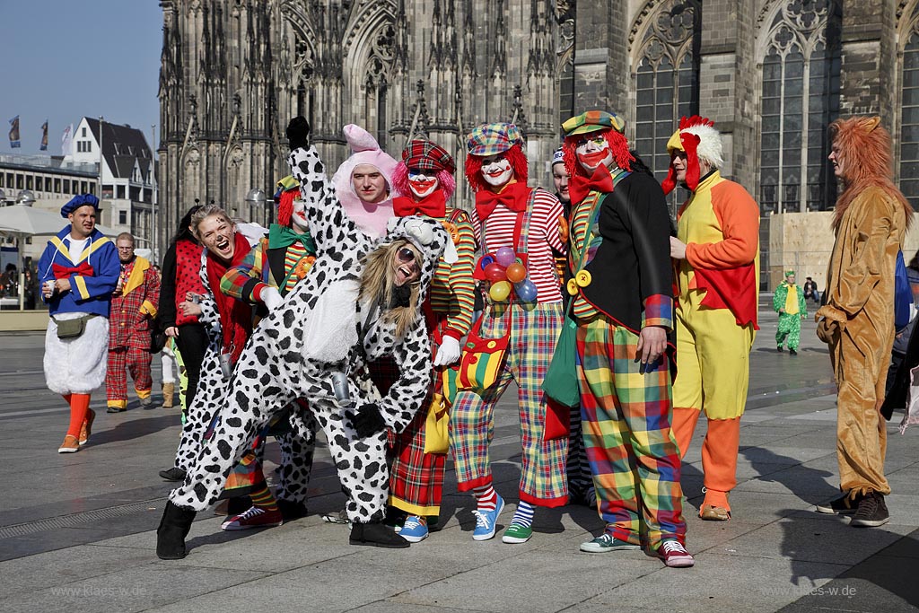 Koeln Domplatte waehrend Altweiberfasnacht, Altweiberfasching, Altweiber feiernde Moehnen und jJecke, verkleidet, Clowns in bunten Kostuemen im Karneval vor dem Dom