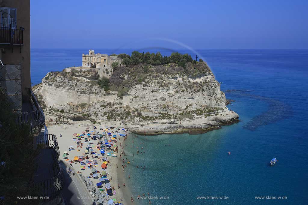 Blick auf die auf einem Felsen gelegene Wallfahrtskirche Chiesa Santa Maria dell'Isola in Tropea, Kalabrien, Italien mit Sicht auf das Meer und Menschen, Touristen am Strand